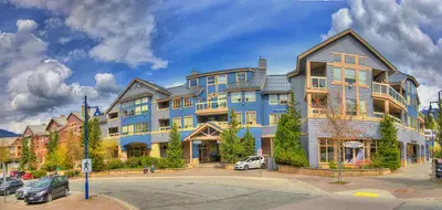 a large blue building with cars parked in front of it at Tyndall Stone Lodge by Whiski Jack in Whistler