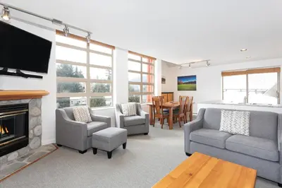 a living room with a fireplace and a tv at Lake Placid Lodge by Whiski Jack in Whistler