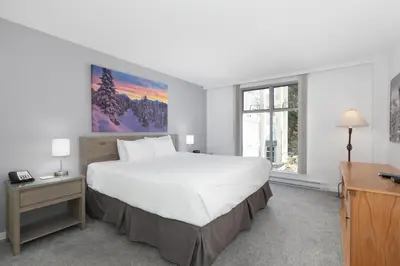 a bedroom with a large white bed and a desk at The Woodrun Lodge by Whiski Jack in Whistler