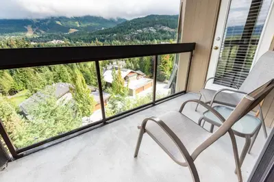a balcony with two chairs and a view of the mountains at The Ironwood on Blueberry Hill in Whistler