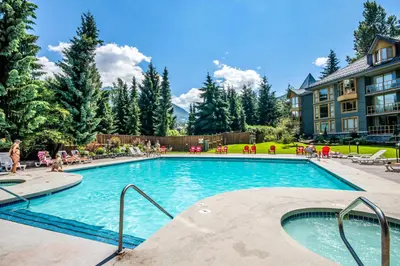 a swimming pool at a resort with people sitting around it at Cascade Lodge by Elevate Vacations in Whistler