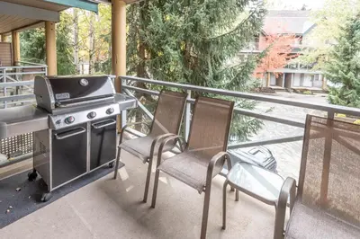 a grill on a balcony with two chairs and a stove at Valhalla Vacations at Whistler in Whistler