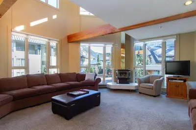 a large living room with a couch and a tv at Village Gate House by Whiski Jack in Whistler
