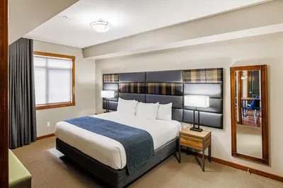 a hotel room with a large bed and a mirror at Stoneridge Mountain Resort in Canmore