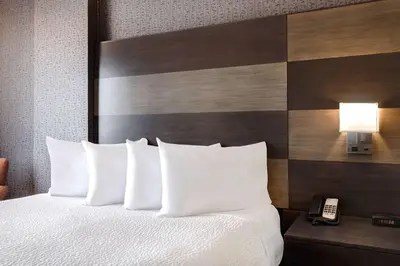 a hotel room with a bed with white pillows and a phone at Days Inn by Wyndham Calgary South in Calgary