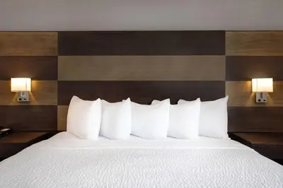 a bed with white pillows in a hotel room at Days Inn by Wyndham Calgary South in Calgary