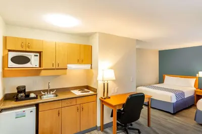 a small hotel room with a bed and a kitchen at Econo Lodge Inn & Suites University in Calgary