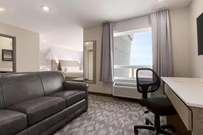 a hotel room with a couch and a bedroom at Days Inn by Wyndham Calgary North Balzac in Balzac