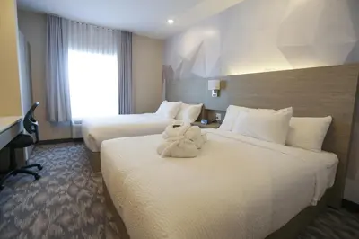 a hotel room with two beds with a stuffed animal on them at Days Inn by Wyndham Calgary North Balzac in Balzac