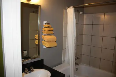 a bathroom with a sink and a shower with towels at Hillcrest Motel in Swan Hills