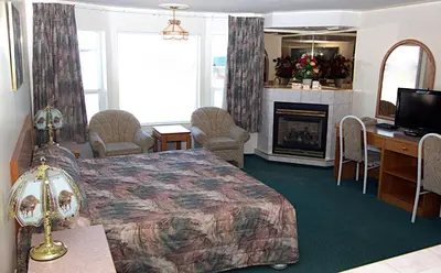 a hotel room with a bed and a fireplace at Western Budget Motel Bonnyville in Bonnyville