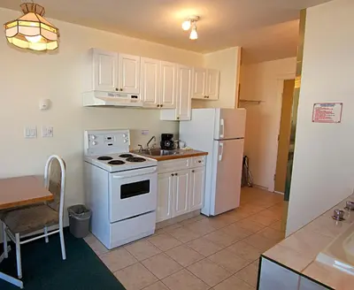 a kitchen with a white refrigerator and a table at Western Budget Motel Bonnyville in Bonnyville