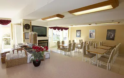 a dining room with tables and chairs and a fireplace at Western Budget Motel Bonnyville in Bonnyville