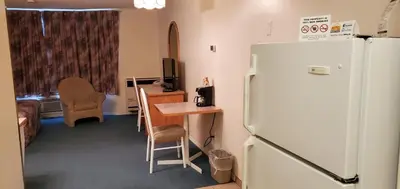 a kitchen with a refrigerator and a table and a desk at Western Budget Motel Cold Lake in Cold Lake