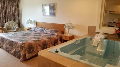 a bedroom with a bed and a bath tub at Western Budget Motel Cold Lake in Cold Lake