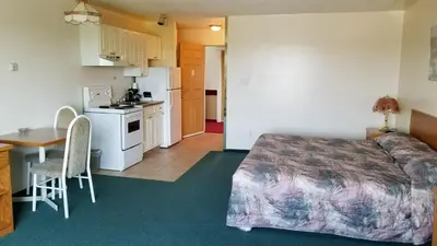 a bedroom with a bed and a kitchen and a table at Western Budget Motel Cold Lake in Cold Lake