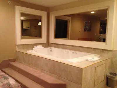 a bath tub in a bathroom with two mirrors at Western Budget Motel Peace River in Peace River