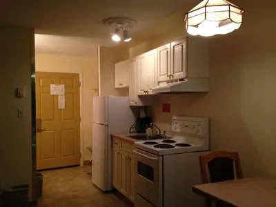 a kitchen with white cabinets and a white refrigerator at Western Budget Motel Peace River in Peace River