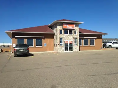 a building with a car parked in a parking lot at Western Budget Motel Peace River in Peace River