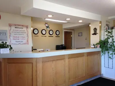 a waiting room with a counter and clocks on the wall at Western Budget Motel Peace River in Peace River