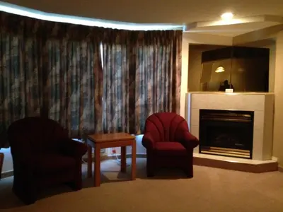 a living room with two chairs and a fireplace at Western Budget Motel Peace River in Peace River