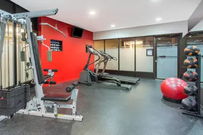 a gym with a red wall and a tread machine at Ramada by Wyndham Kelowna Hotel & Conference Center in Kelowna