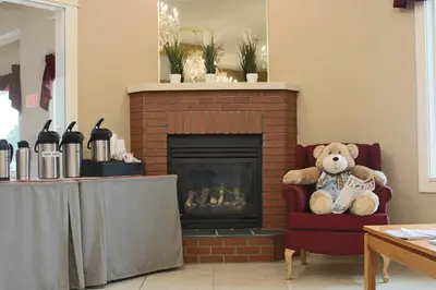 a teddy bear sitting in a chair next to a fireplace at Western Budget Motel Ponoka in Ponoka