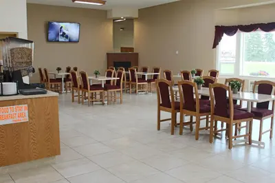 a dining room with tables and chairs and a tv at Western Budget Motel Ponoka in Ponoka