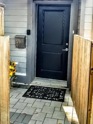 a black door with a mat in front of it at New Urban Modern Main Street House in Vancouver