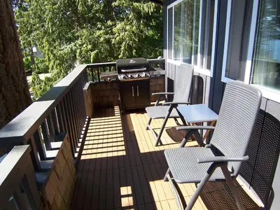 a porch with two chairs and a grill on it at Malaspina Strait Cottage in Powell River