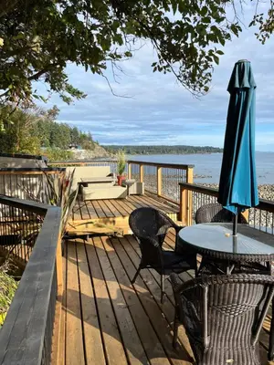 a deck with a table and chairs and an umbrella at Malaspina Strait Cottage in Powell River