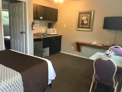 a room with a bed and a desk and a kitchen at Fuller Lake Chemainus Motel in Chemainus