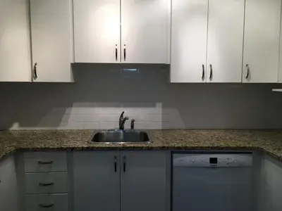 a kitchen counter with a sink and white cabinets at Twelve Oaks By Marquee Vancouver in Vancouver