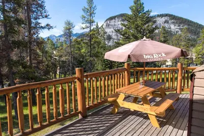 a picnic table with an umbrella on a deck at HI Banff Alpine Centre - Hostel in Banff