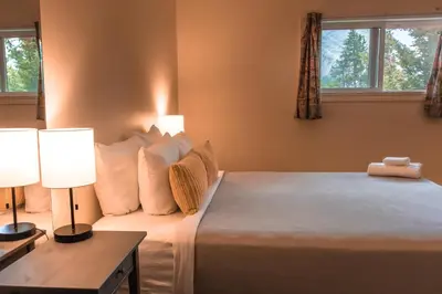 a bedroom with a bed and two lamps and two windows at HI Banff Alpine Centre - Hostel in Banff