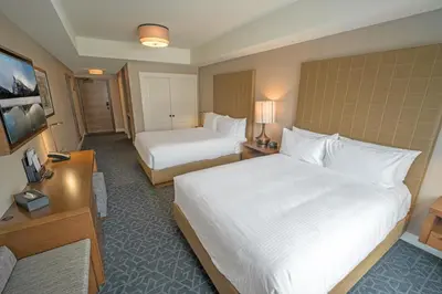 a hotel room with two beds and a television at The Malcolm Hotel in Canmore