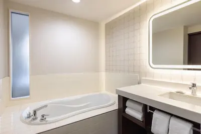 a bathroom with a tub and a sink and a mirror at Delta Hotels by Marriott Grand Okanagan Resort in Kelowna