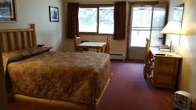 a bedroom with a bed and a desk and windows at Yellowhead Motel in Valemount