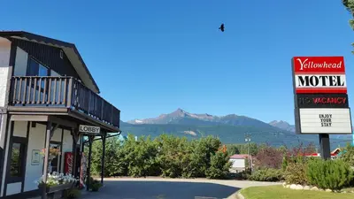 a motel with a sign and mountains in the background at Yellowhead Motel in Valemount