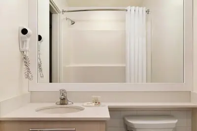 a bathroom with a sink and a mirror and a toilet at Days Inn by Wyndham 100 Mile House in One Hundred Mile House