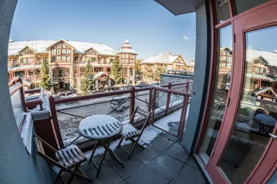 a balcony with chairs and a table and a view of a building at Alpenglow Lodge by Bill in Whistler