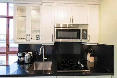 a kitchen with white cabinets and a sink and a microwave at Alpenglow Lodge by Bill in Whistler