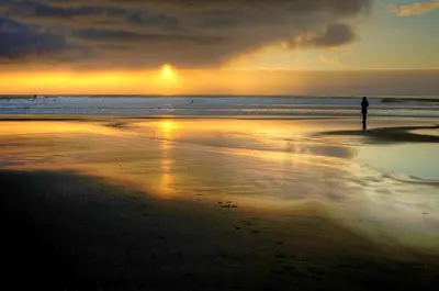 a person standing on the beach at sunset at Waters Edge Shoreside Suites in Ucluelet