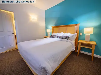 a bedroom with a large bed and a blue wall at Waters Edge Shoreside Suites in Ucluelet