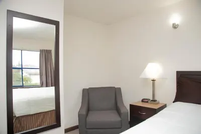 a bedroom with a bed and a chair and a mirror at Happy Day Inn in Burnaby