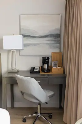 a desk with a white chair and a table with a lamp at The Thompson Hotel in Kamloops