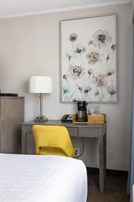 a bedroom with a desk with a bed and a yellow chair at The Thompson Hotel in Kamloops