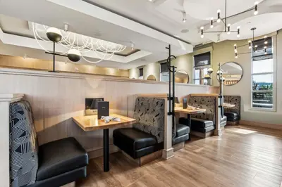 a restaurant with black chairs and tables and a bar at Sandman Signature Calgary Airport Hotel in Calgary