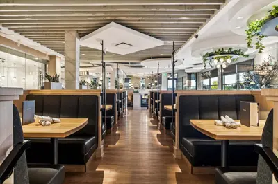 a dining room with wooden tables and black chairs at Sandman Signature Calgary Airport Hotel in Calgary