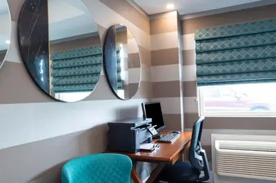 an office with a desk with a computer and a mirror at Sandman Signature Calgary Airport Hotel in Calgary